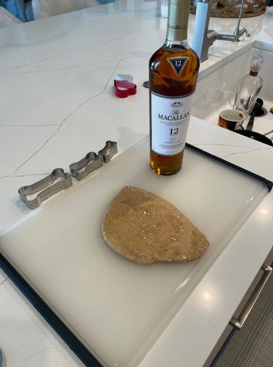 A bottle of whiskey and some food on top of a counter.